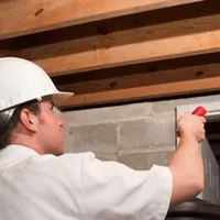 Termite inspection technician checking a basement wall and framing for termite activity in Austin, TX